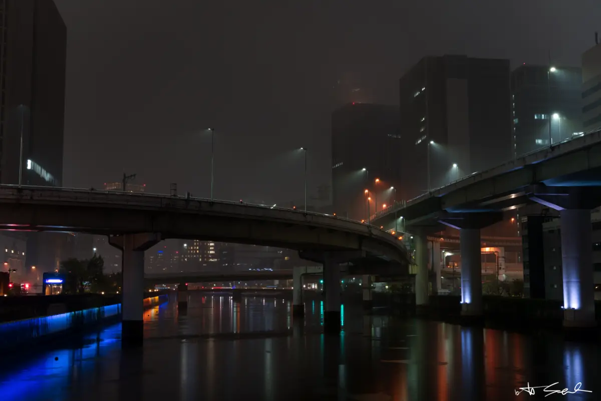 Hochstraße über einem Fluss bei Nacht im Regen
