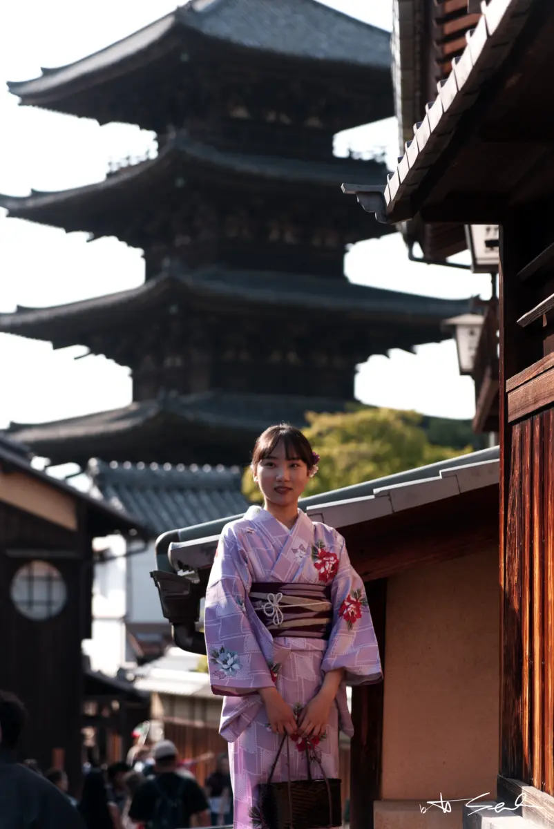 Frau im violetten Kimono in einer Gasse vor einer Pagode