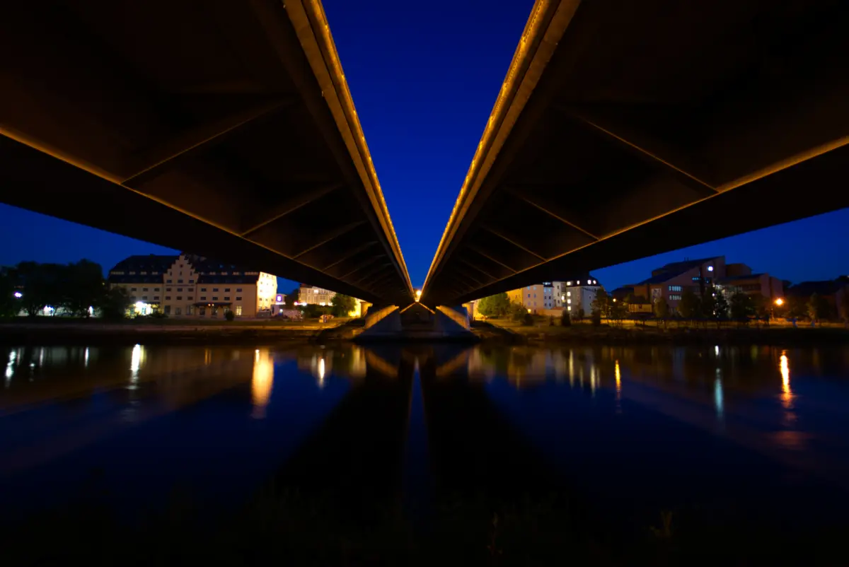 Unterseite einer Brücke über einem Fluss bei Nacht