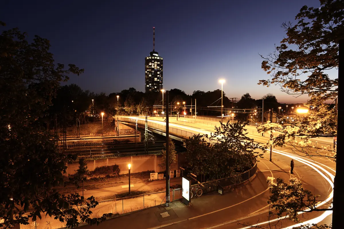 Stadt in der Dämmerung mit Hochhausturm und Lichtspuren auf der Straße