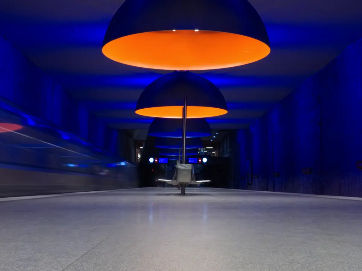 U-Bahnhof mit blauem Licht und großen orangefarbenen Lampenschirmen
