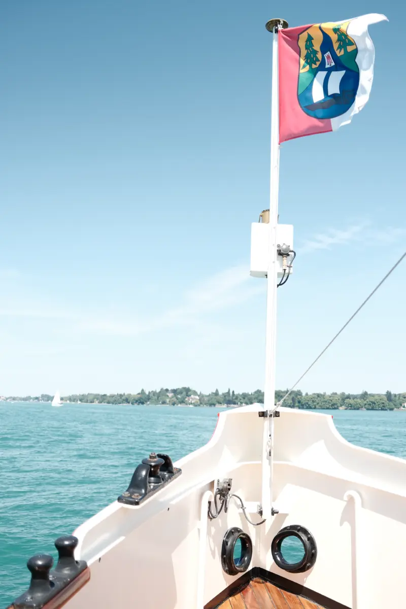 Wappenflagge am Bug des Dampfers über dem türkisfarbenen See