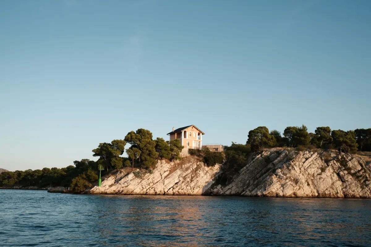 Felsige Insel mit kleinem Haus und Kiefern im Abendlicht