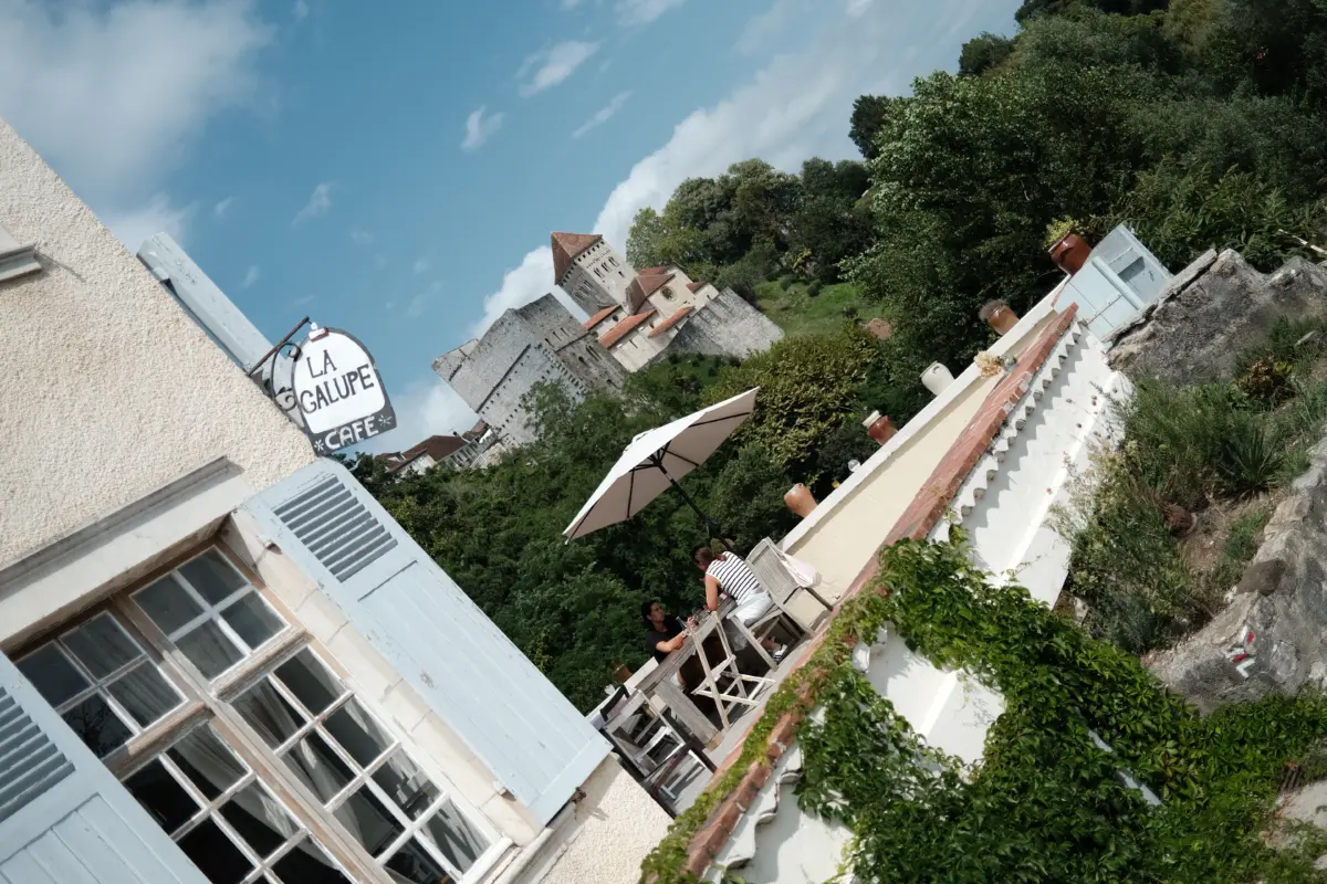 Schräger Blick auf ein Haus mit Café-Schild und begrünter Terrasse