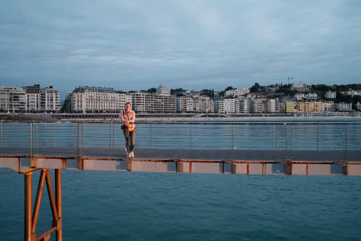 Person auf einem Steg vor der Stadtkulisse am Meer