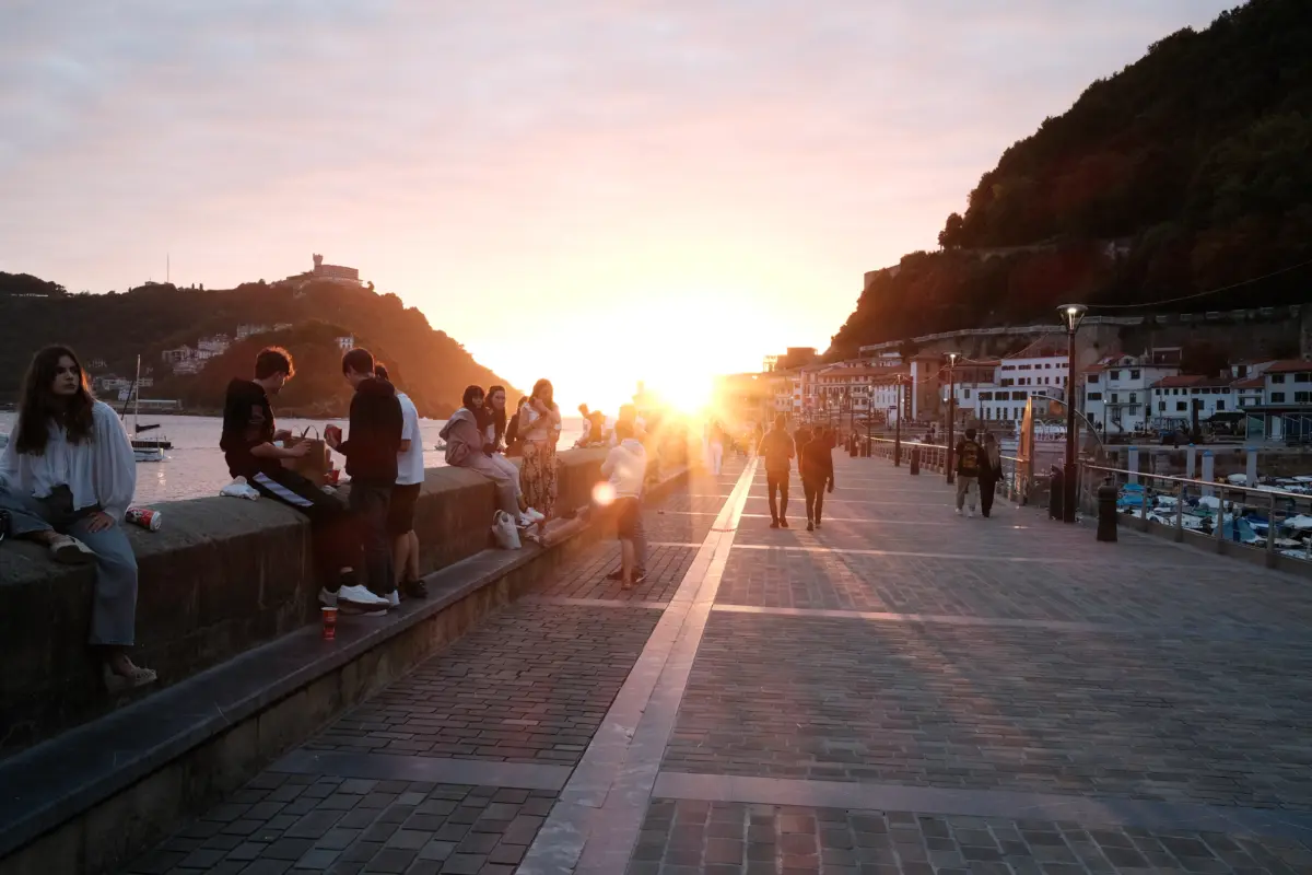 Menschen auf der Hafenpromenade im Gegenlicht der untergehenden Sonne