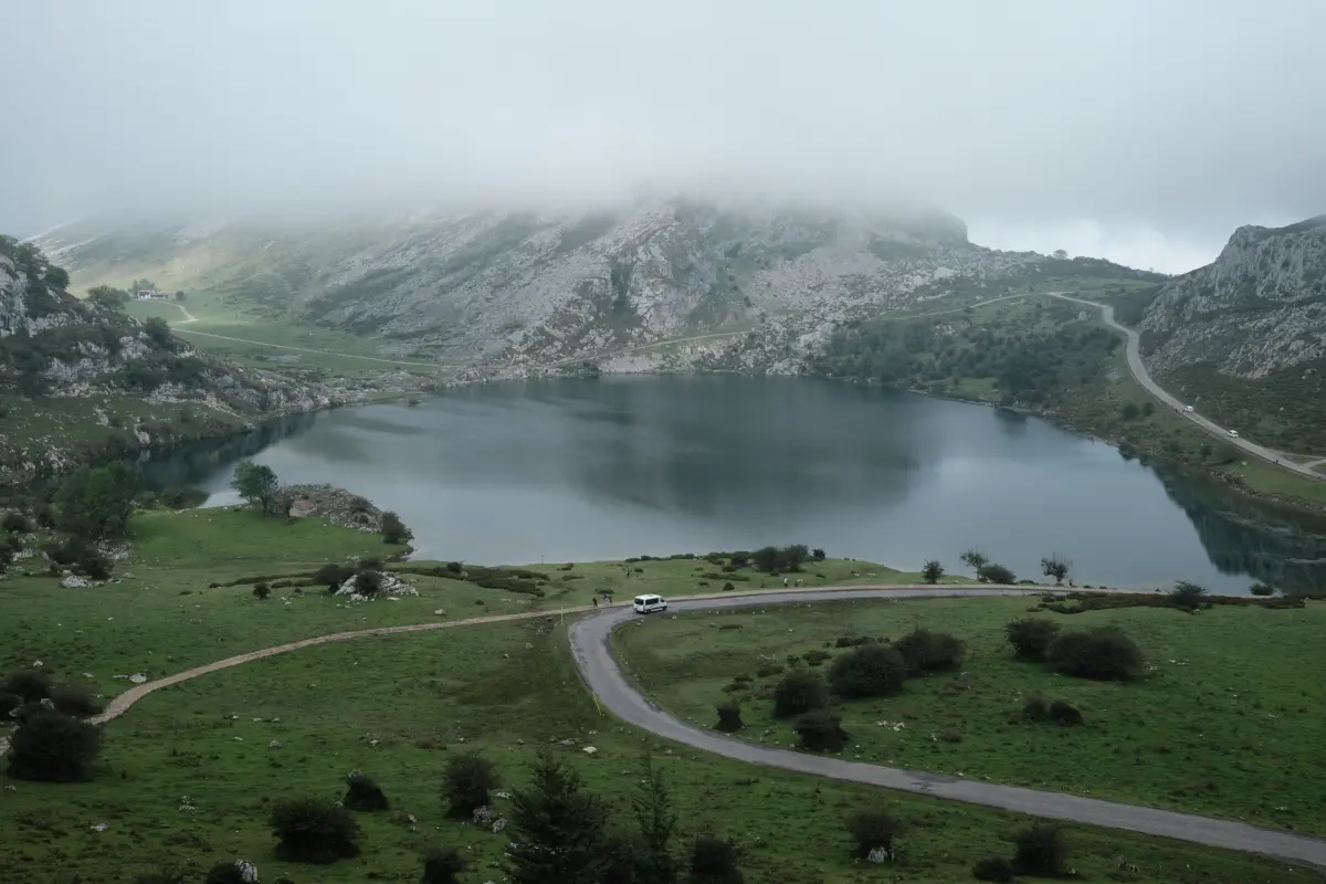 Bergsee zwischen grünen Hängen unter tiefen Wolken