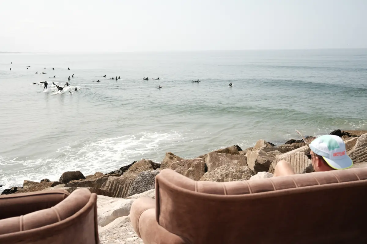 Surfer im Meer, im Vordergrund Sessel auf den Felsen