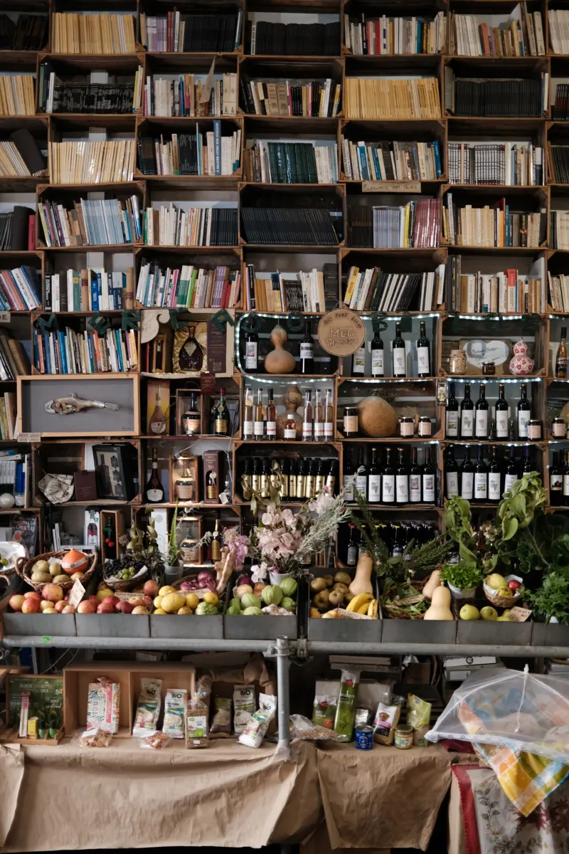 Buchhandlung mit Regalen voller Bücher, Wein und Obst
