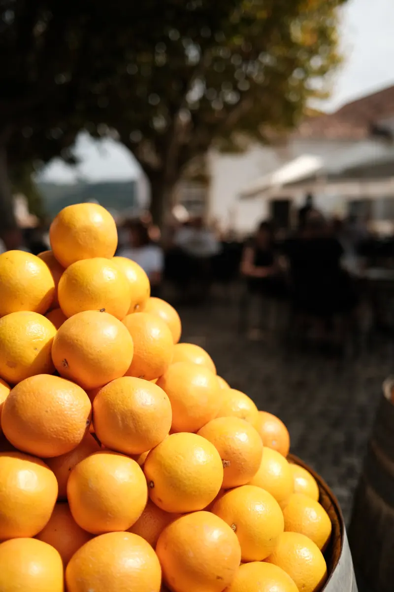 Haufen frischer Orangen im Vordergrund eines Platzes