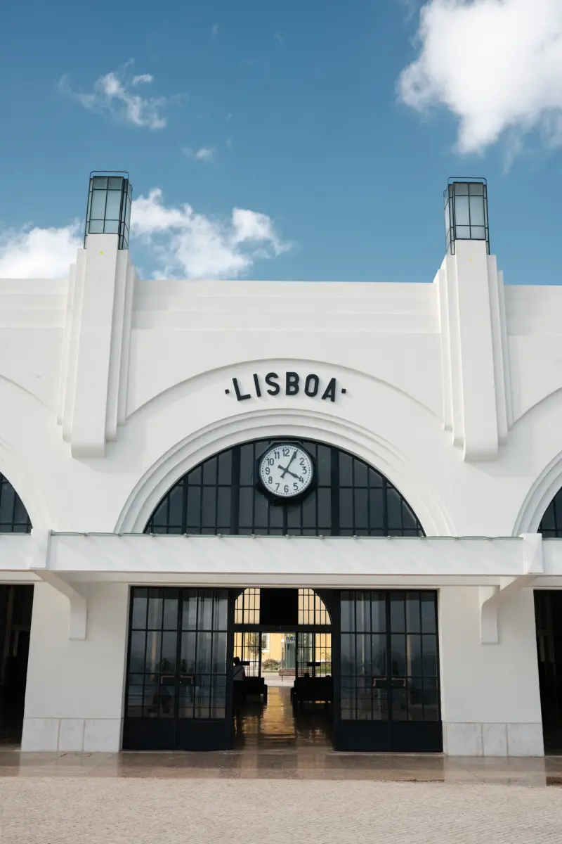 Weißes Bahnhofsgebäude mit Uhr und Schriftzug „Lisboa“