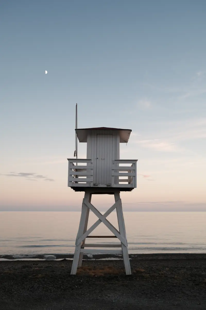 Weißer Rettungsschwimmerturm am Strand in der Dämmerung