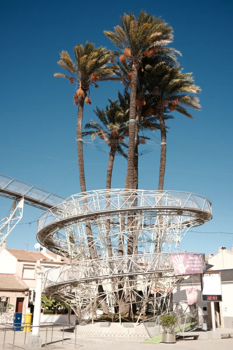 Palmen hinter einer spiralförmigen Metallskulptur