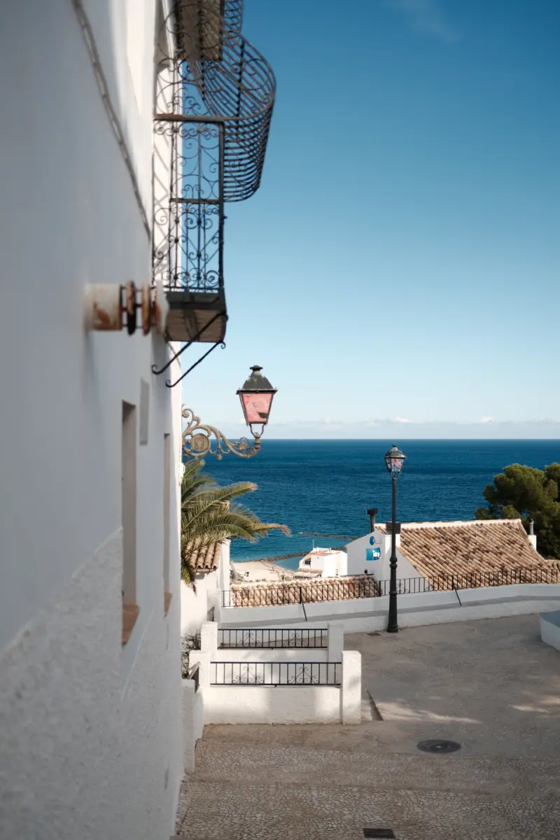 Weiße Gasse mit Laterne und Blick aufs Meer