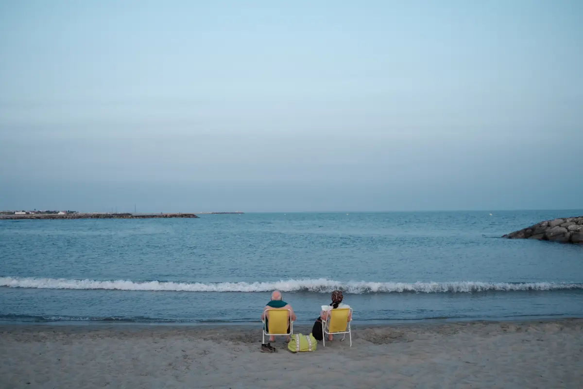 Zwei Personen in Strandstühlen am Meer in der Dämmerung