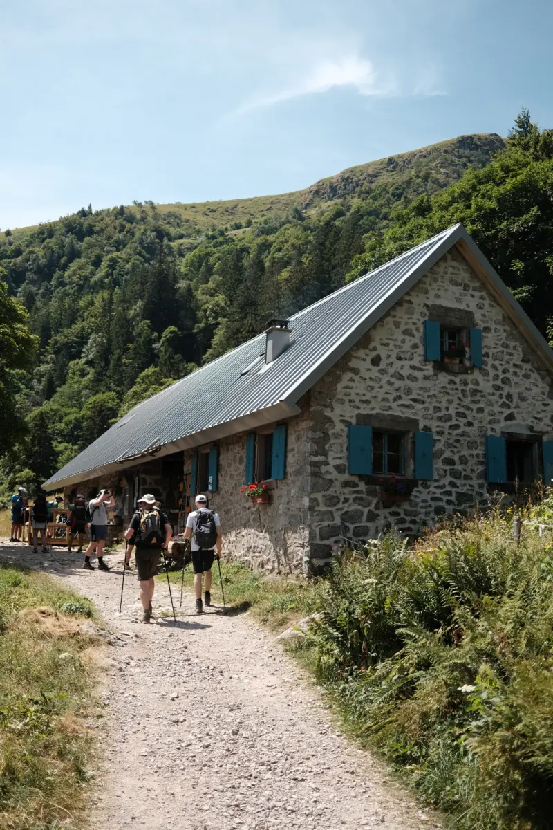 Wandergruppe auf einem Pfad vor einer Steinhütte
