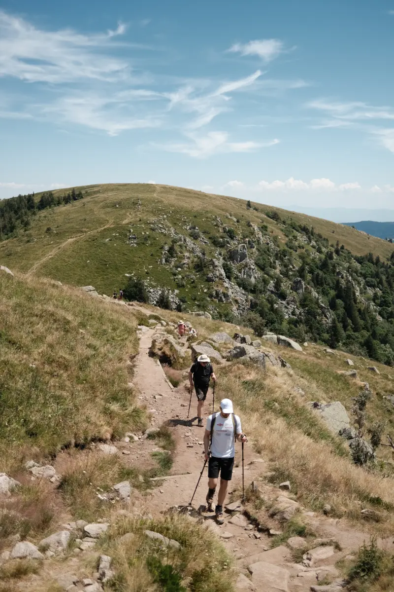 Zwei Wanderer auf einem Pfad über einen Bergrücken